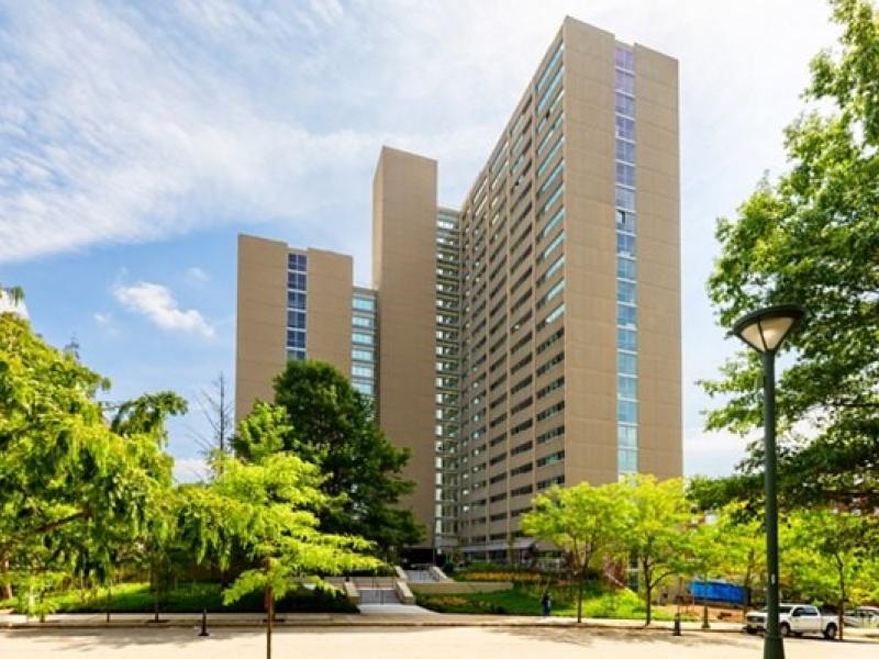 View of high rise apartment building surrounded by pathways and trees 