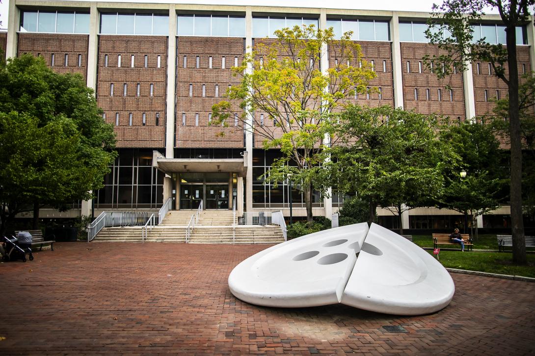 Giant aluminum sculpture of a button split in half, with Penn's Van Pelt Library in the background.