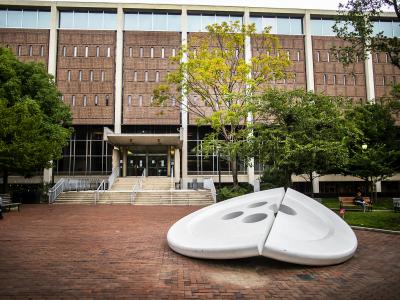 Giant aluminum sculpture of a button split in half, with Penn's Van Pelt Library in the background.