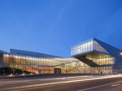 Lit up modern facade of the Singh center against a blue evening sky 