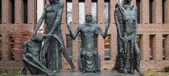 Large statue of three female figures with arms outstretched 